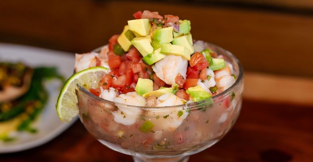 A dish served in a cocktail glass with diced avocado, tomatoes, and onions, accompanied by crispy tortilla chips on a white plate at Shaver Lake Village Hotel.