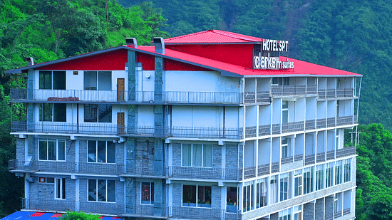 Facade of SPT Clarks Inn Suites, Mandi amidst lush greenery with a glimpse of a mountain in the bakcground