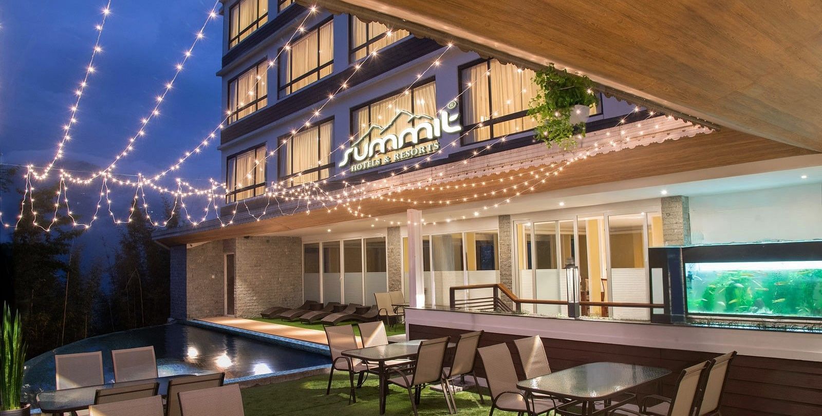 A pool side dining arrangement illuminated by hanging lights - Summit North Star, Gangtok