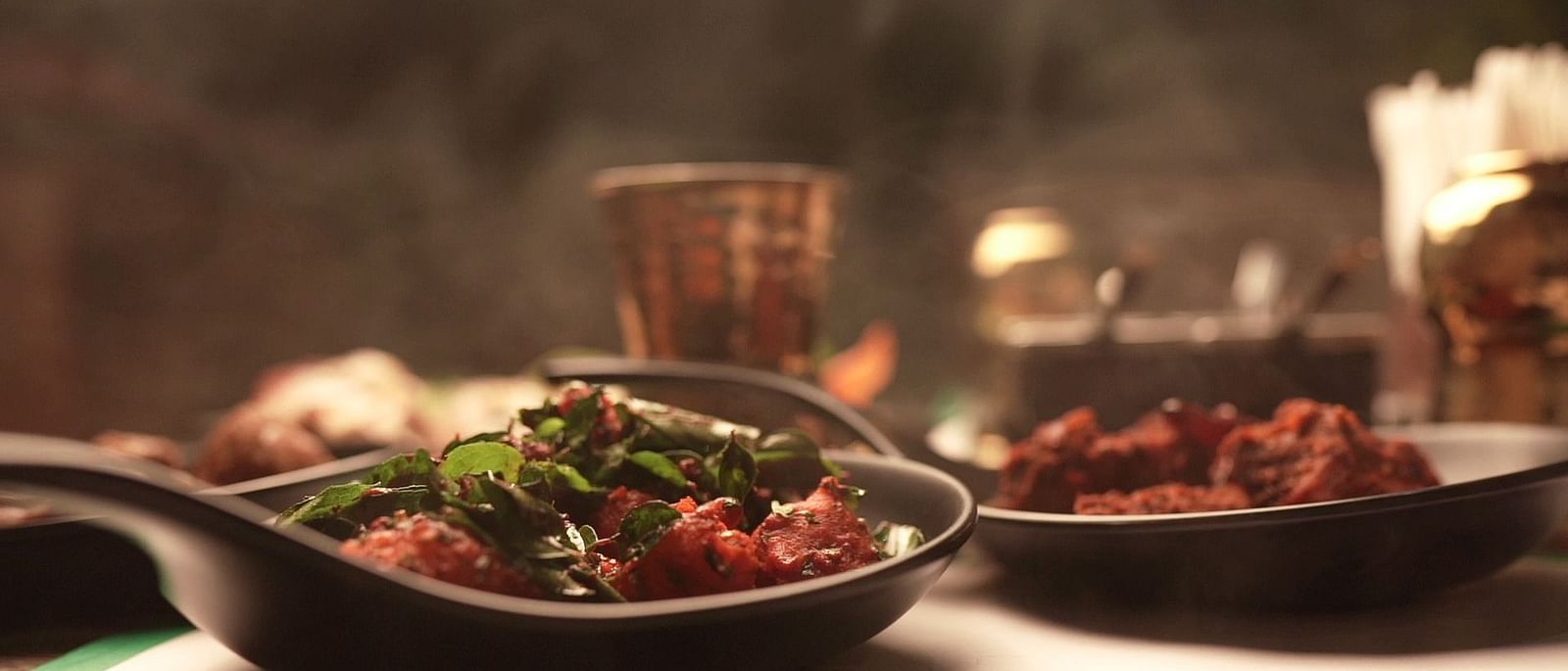 An image of a chicken fry seasoned with curry leaves served in a pan - Pai Group of Hotels