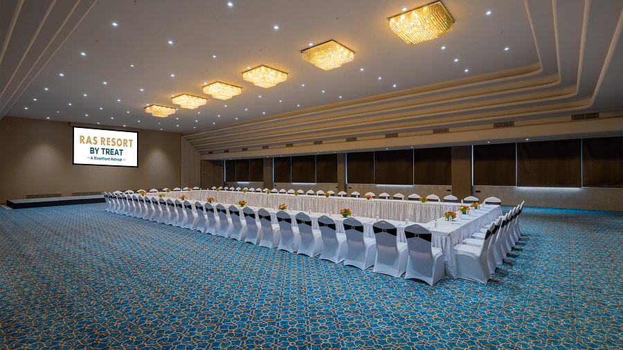 A grand banquet hall at Ras Resort by Treat, Silvassa, with a long rectangular table and chairs set up for a conference or meeting.
