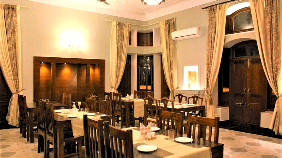 Hotel Devnadi, Haridwar | A dining space with chairs, tables, and a fan.