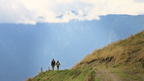A couple standing on top of a hill looking at the mountains on the other side