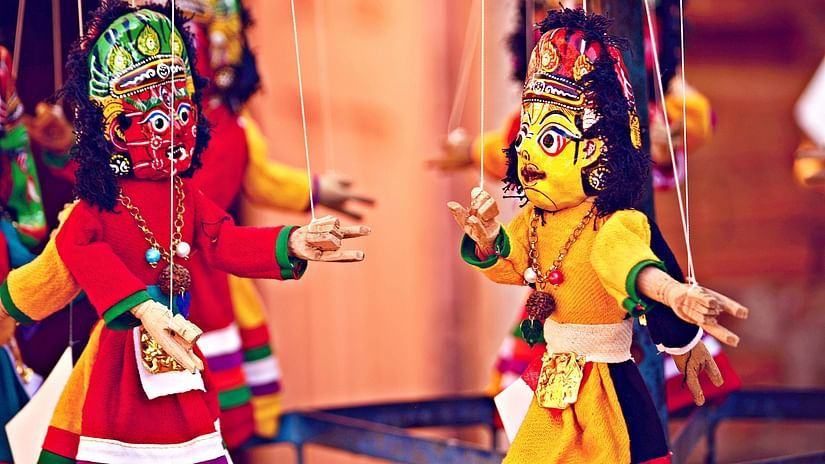 two puppets being controlled by a puppet master during a puppet show
