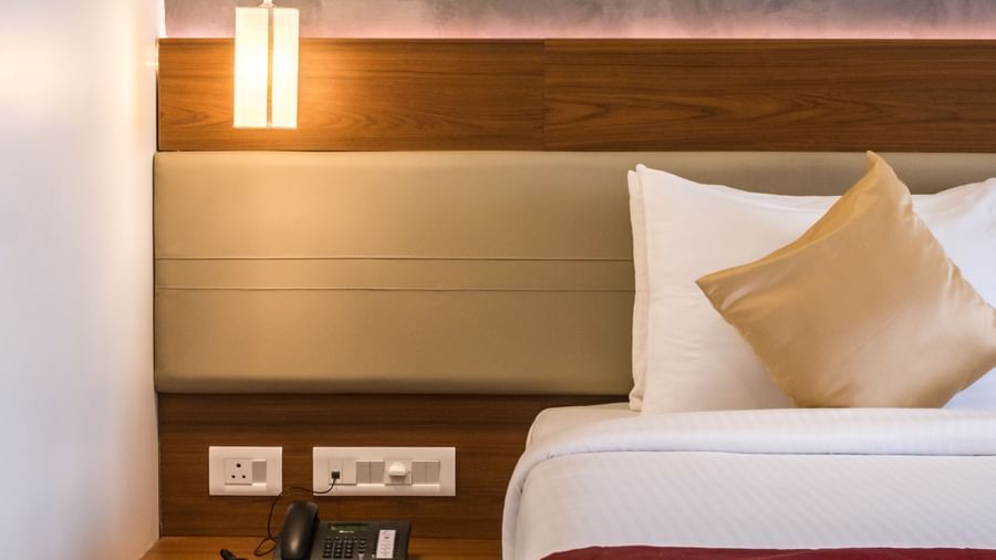 A comfortable hotel bedroom with a large bed, stylish headboard, and bedside table with a lamp at Shilton Dee Cee.