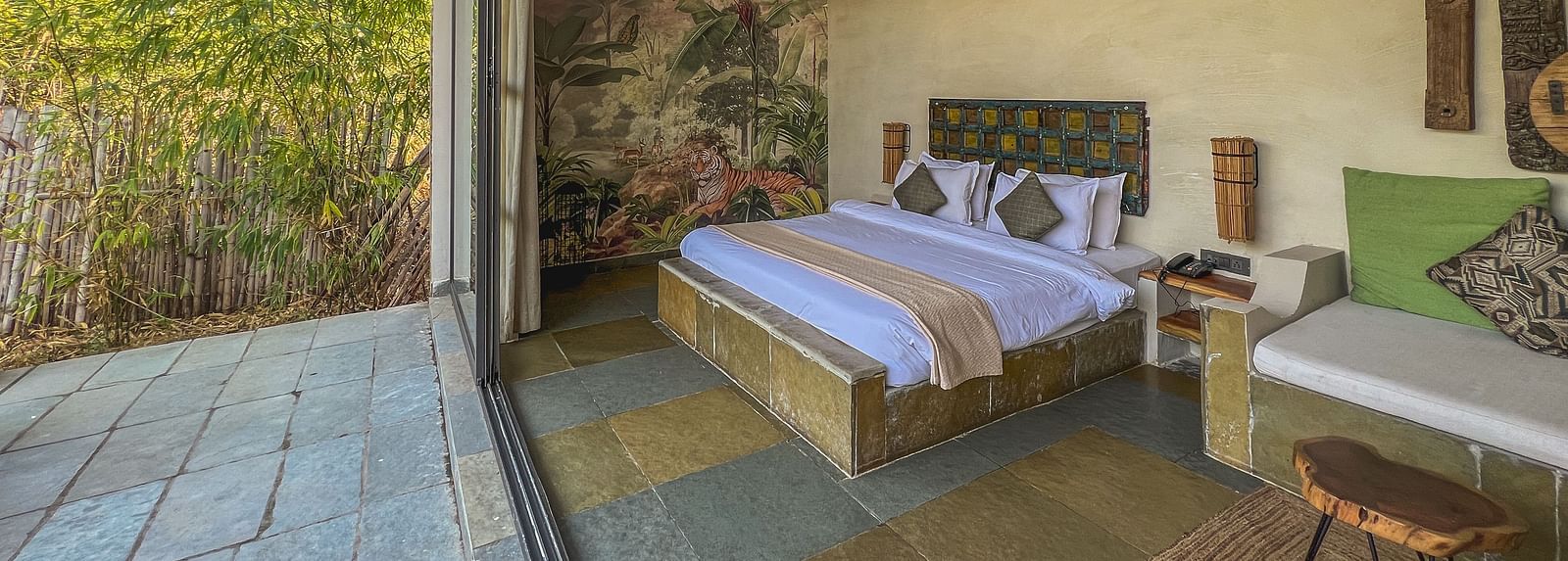 An image of the Stone Cabin with a large bed, a ceiling fan and comfortable furniture - Utsav Camp