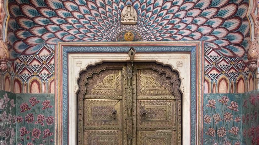 An overview of the lotus gate of City Palace in Jaipur with a peacock design on the roof above the door