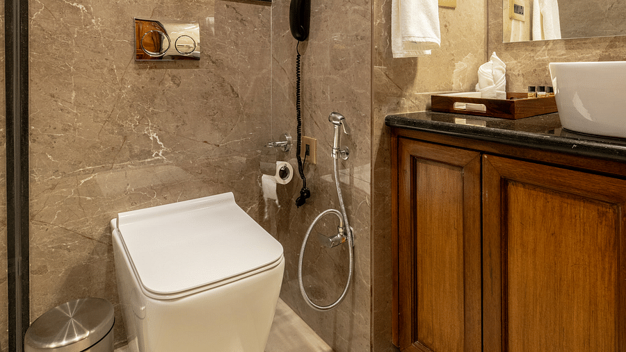 A washroom with the shower area, a toilet seat, and other toiletries - Brij Castle, Jaipur
