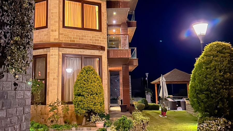 Nighttime view of the illuminated Aranya Retreat villa with manicured gardens and peaceful ambiance in Mashobra