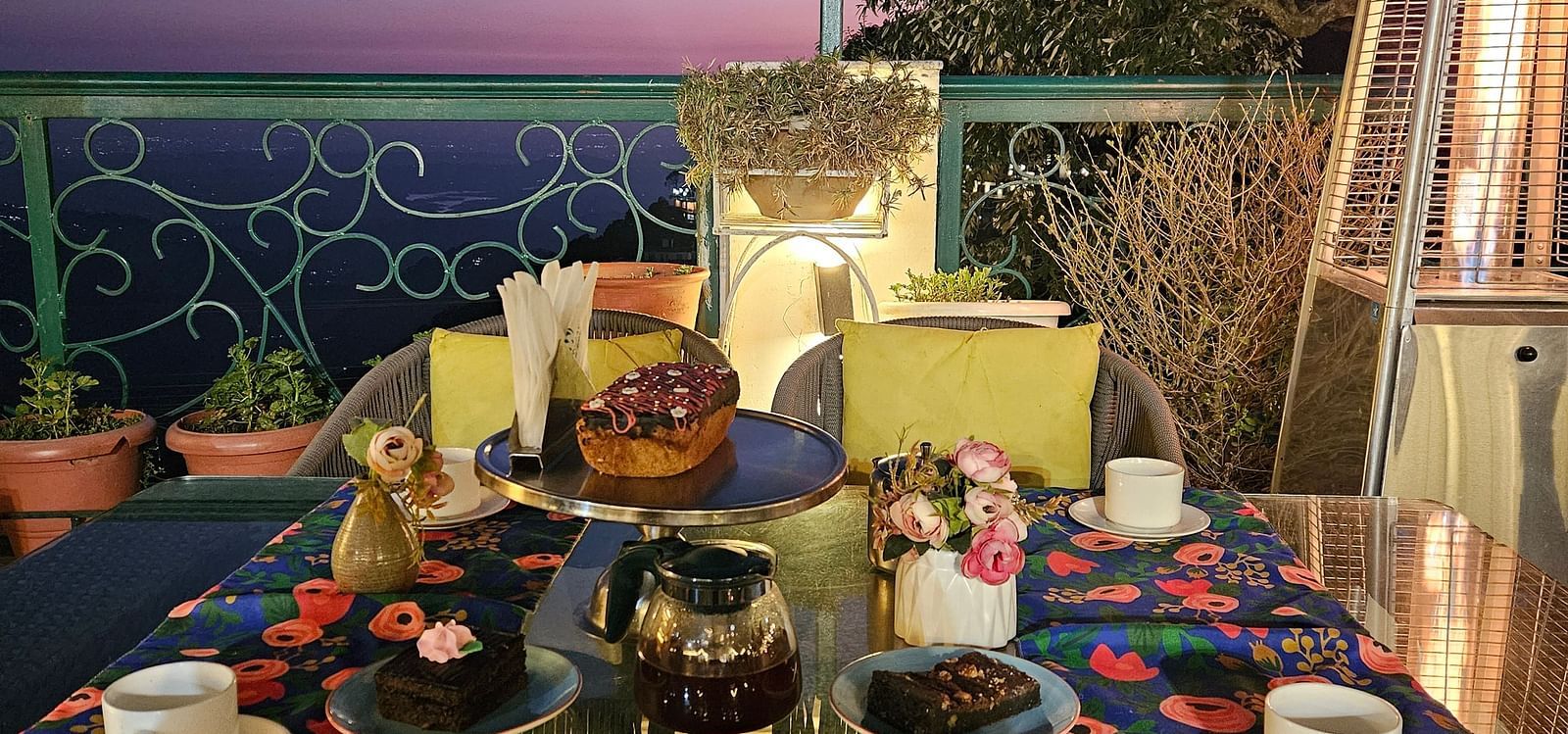A terrace with tables set for dining under ambient lighting, offering sunset views | Mongas Hotel & Resort, Dalhousie 