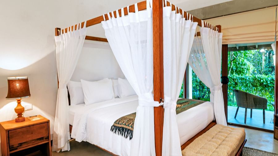 Cozy four-poster bed with white drapes and nature view