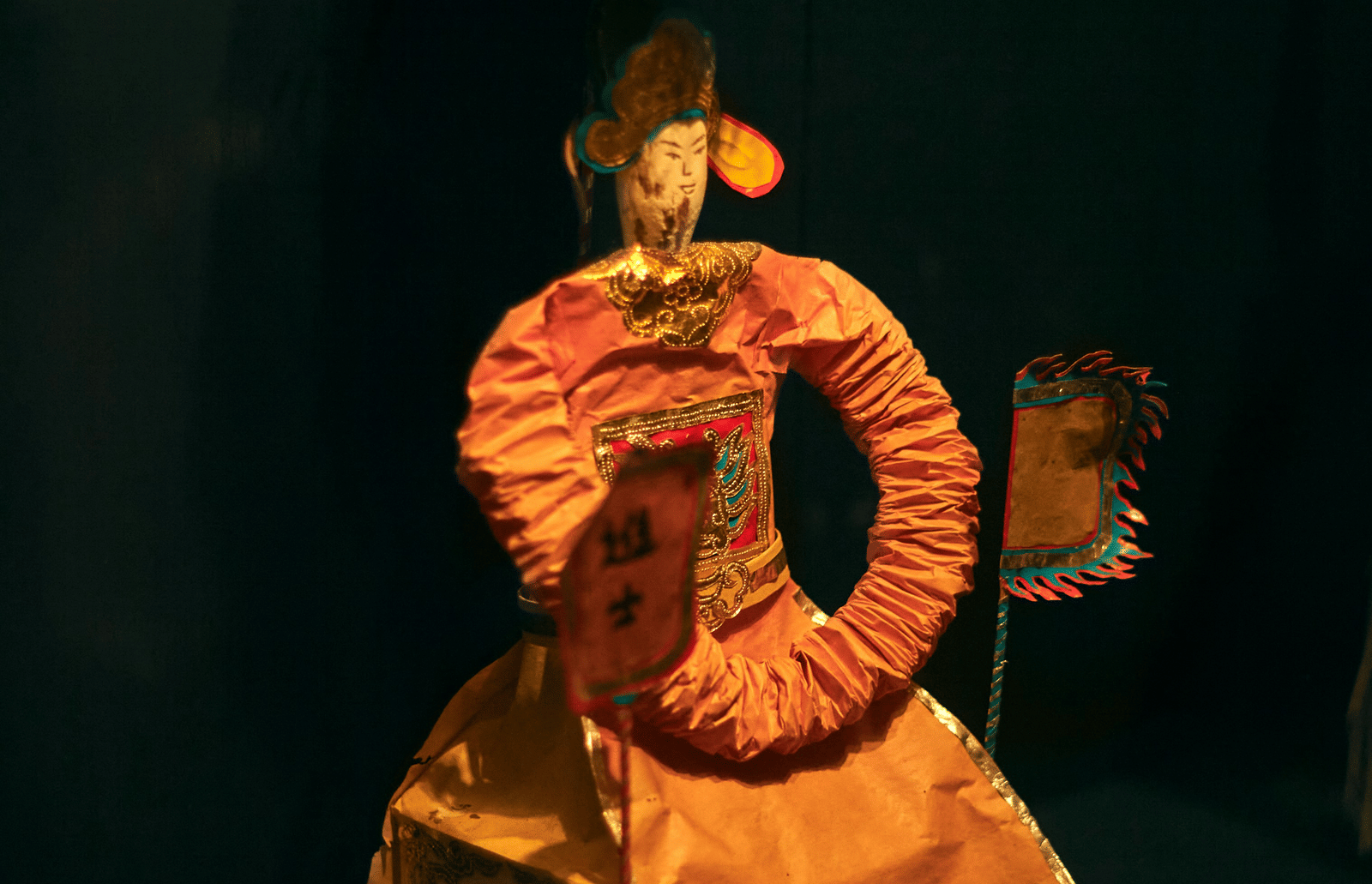 A close up of a traditional Vietnamese puppet with a black background, showcased during Life Puppets Show Nha Trang.