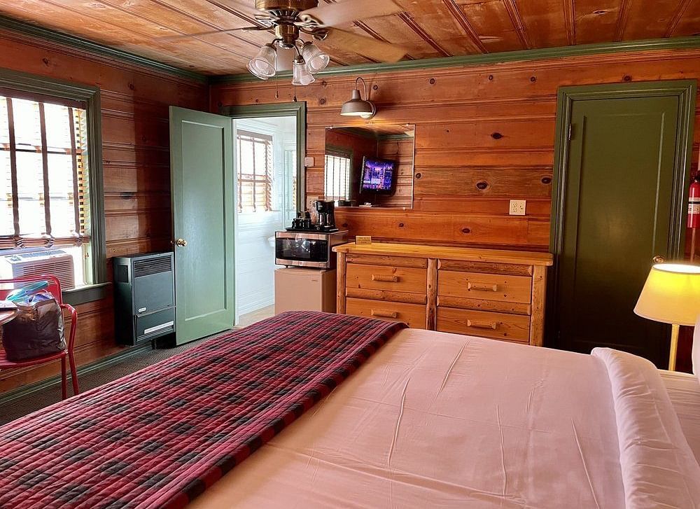 a room at Shaver Lake Village Hotel with a double bed, a cabinet, and wood paneling and furniture throughout.