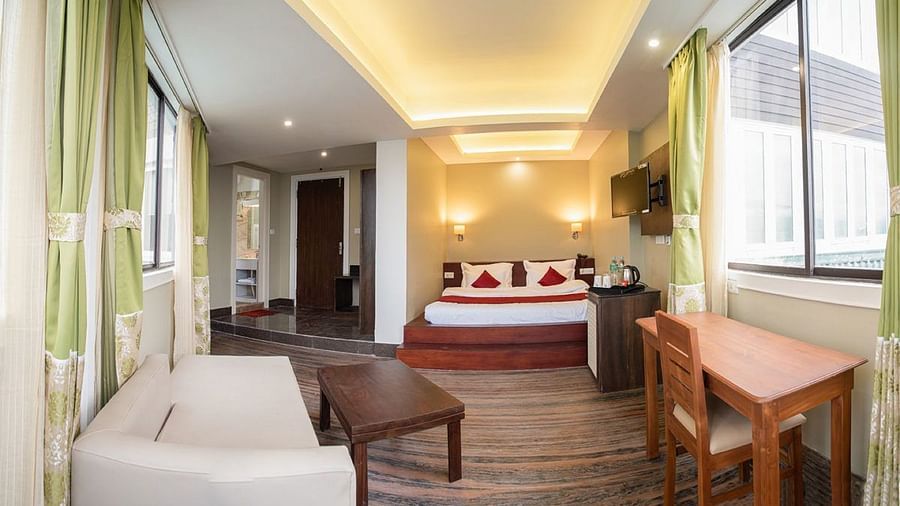 A view of a hotel room featuring a sofa, a teapoy, a writing desk, and a plush size bed - Summit North Star, Gangtok