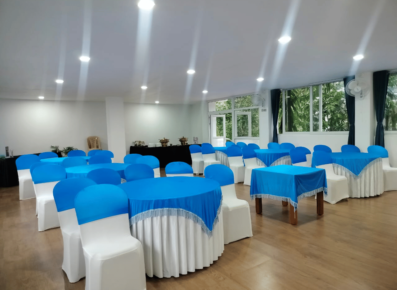 An event space set up with chairs and tables draped in white and vibrant blue covers at Coorg Orange Blossom Resort and Spa.