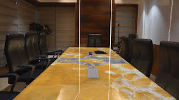 Front view of the long marble table at the boardroom at SRS Suites, Koramangala, surrounded by black office chairs.