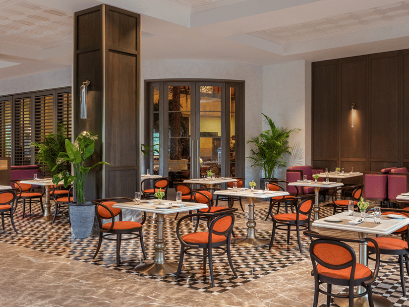 Corner view of the Carnaby dining area at The Residency Towers Chennai, featuring warm ambiance, arranged tables, chairs, and indoor plants.