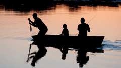 silhouettes of two adults and a child on a boat rowing to reach a destination 
