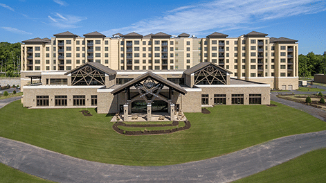 Exterior of YO1 Longevity & Health Resorts with a parking way running in front of it on a sunny day under blue sky .