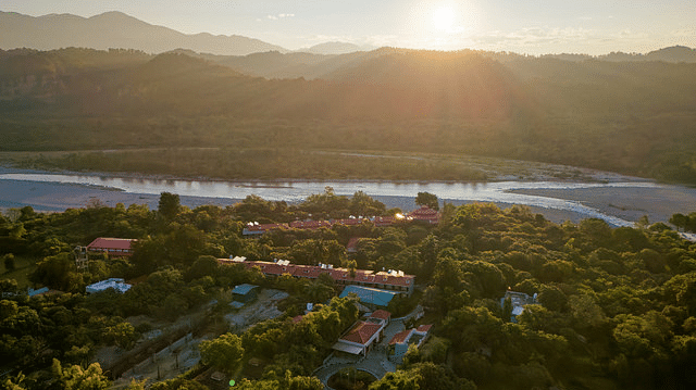 Scenic river valley view with mountains and resort buildings at sunset.