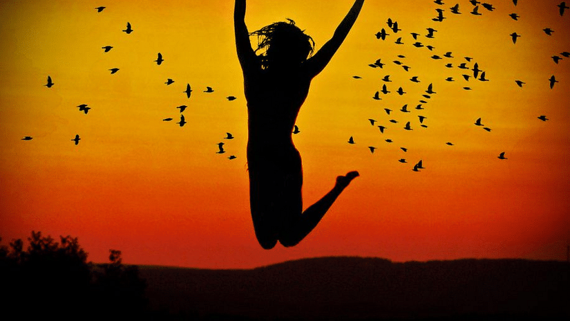 Woman jumping in the air with the evening sky in the background