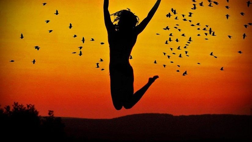 Woman jumping in the air with the evening sky in the background
