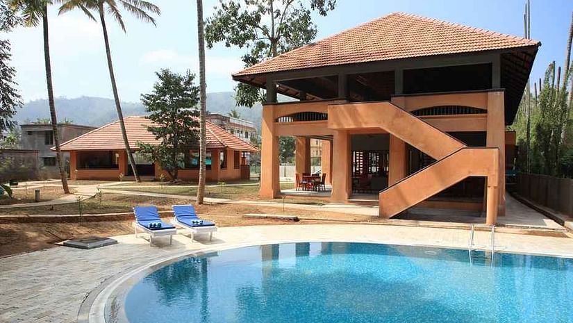 An overview of the swimming pool with loungers and a building next to it - Abad Green Forest, Thekkady.