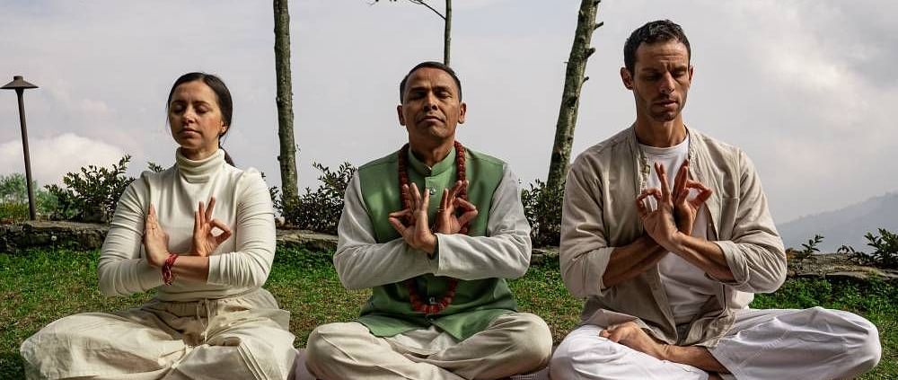 A front shot of three people sitting on the grass and meditating | Kavya Resort & Spa, Nagarkot