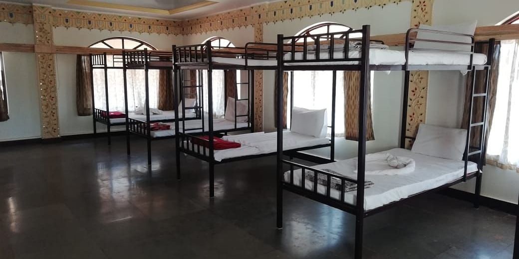 A diagonal view of the dormitory at Riverside Inn with bunk beds side by side and light streaming through the windows.