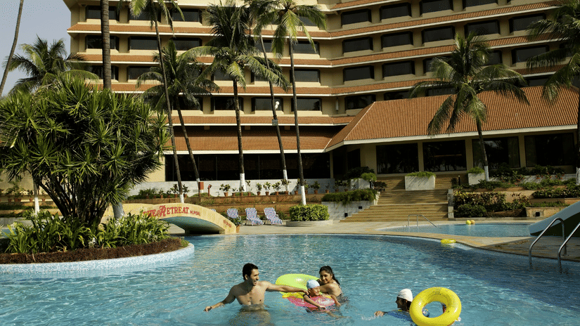 The Retreat Hotel and Convention Centre exterior view showing the large swimming pool with guests relaxing, surrounded by landscaped greenery and the hotel building in the background.