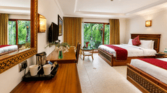 Executive Room with twin beds, a seating nook and garden view through the window at Chariot Beach Resort.