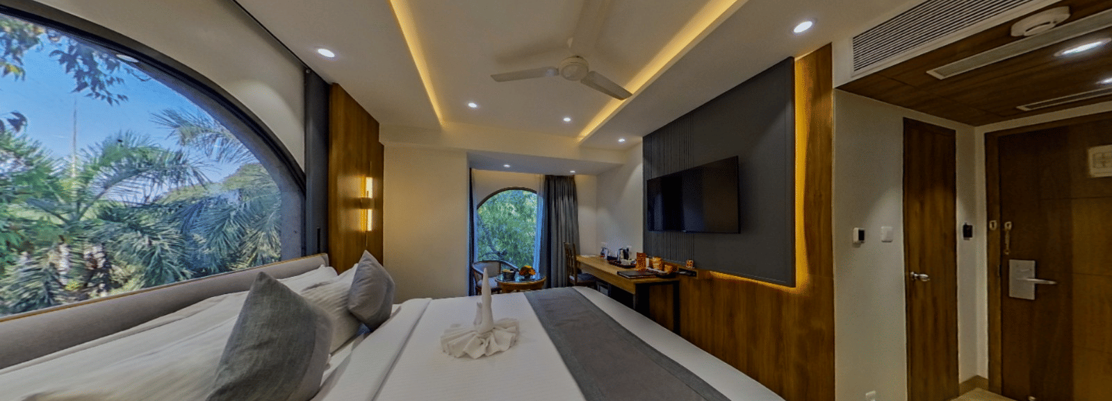 The Standard Room at Lords Inn Vadodara, with a bed placed near a large window, extended wall panelling, and ambient ceiling lights.