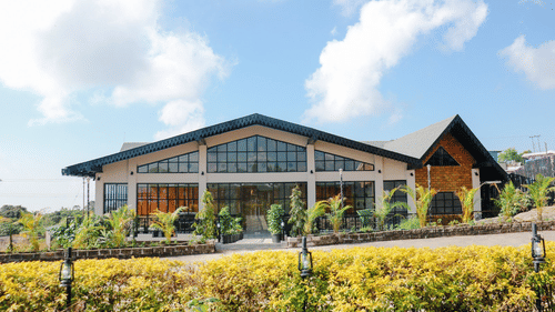 The Mausmai Ballroom features a grid-patterned glass facade, flooding the space with natural light and offering panoramic views of the lush garden outside.