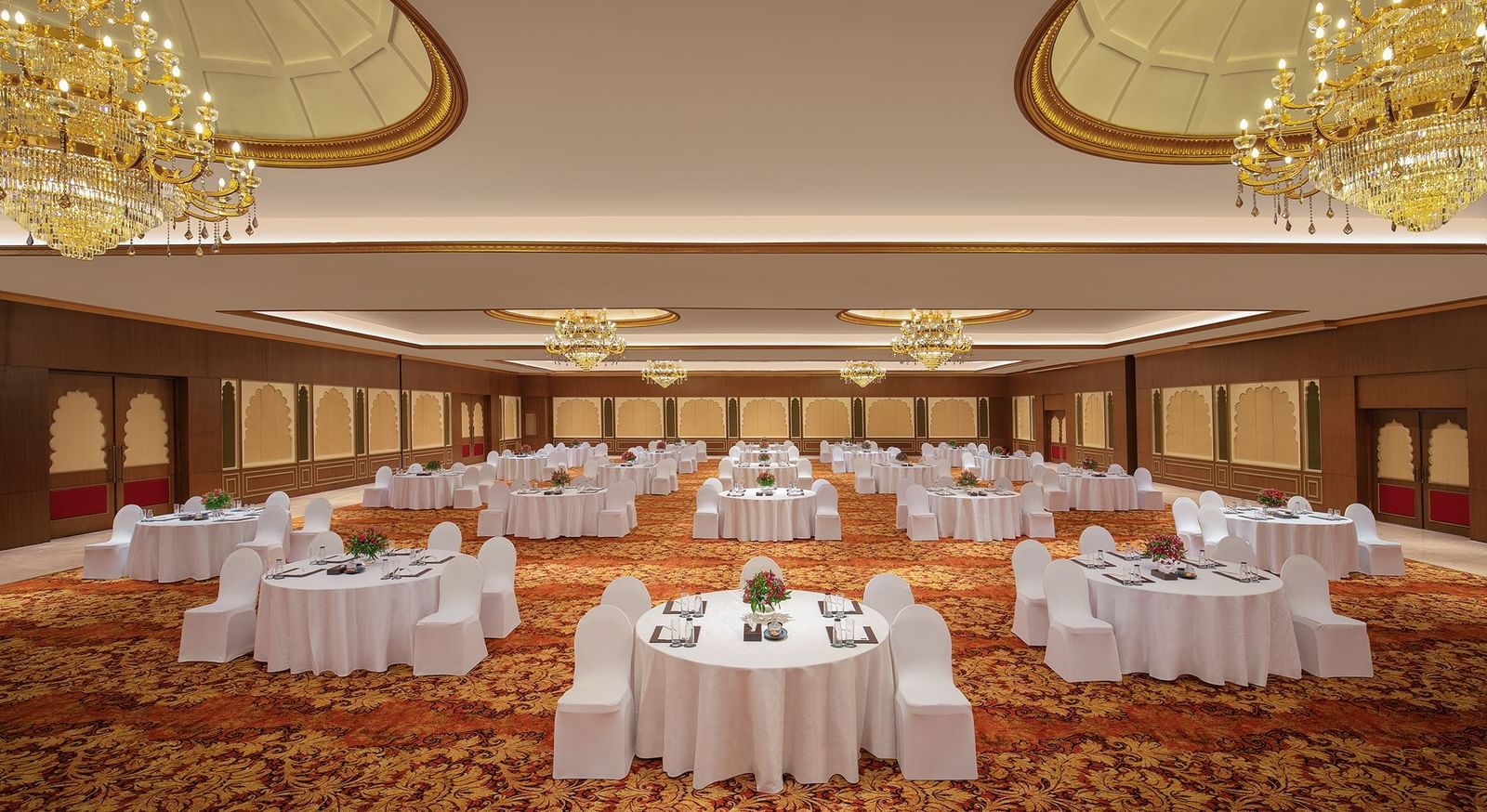 A banquet hall in Mahabalipuram with chandeliers, carpeted floors, and a cluster-type seating arrangement – Kaldan Samudra Palace, a Beautiful Wedding Venue ECR