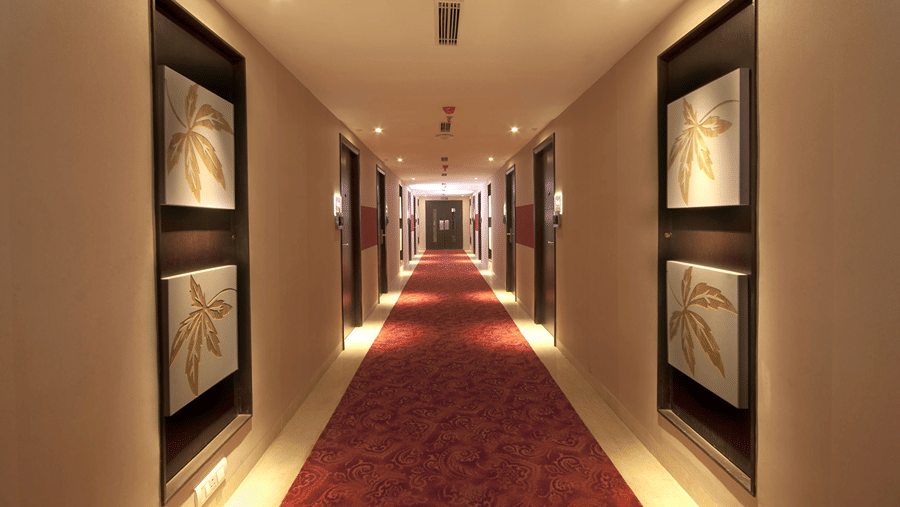 A brightly lit corridor layered with red carpet and several doors leading to other Executive Rooms - Senses Hotel