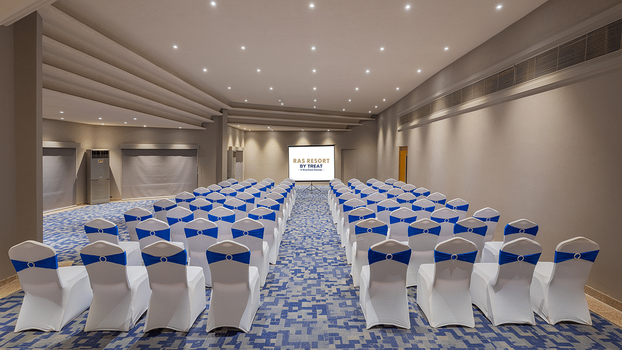 A spacious conference hall at Ras Resort by Treat, Silvassa, with rows of chairs set up for a event.