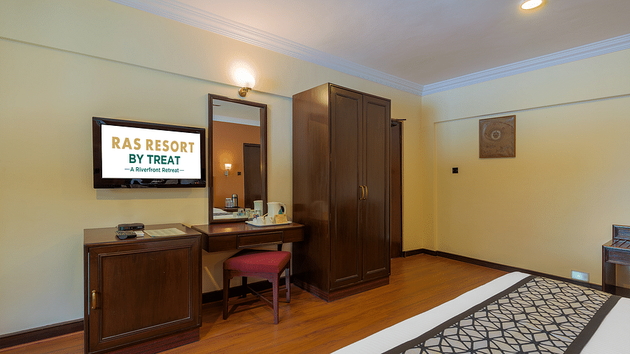 A well-furnished room at Ras Resort by Treat, Silvassa, featuring a comfortable bed, a dressing table, and a television.