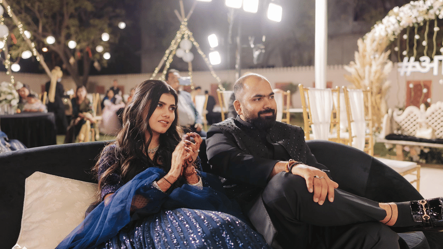 Couple enjoying a relaxed moment at an evening wedding event with ambient lighting.