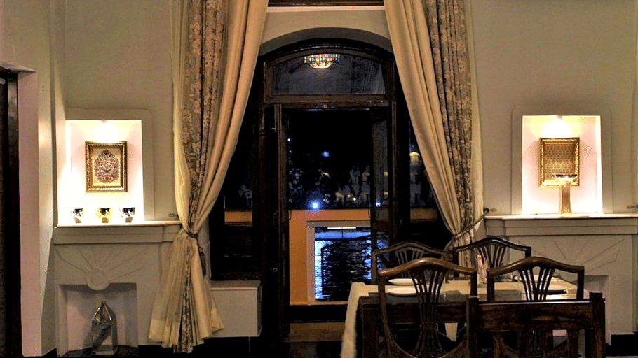 A room with tables, chairs, lights, and a window. | Hotel Devnadi, Haridwar