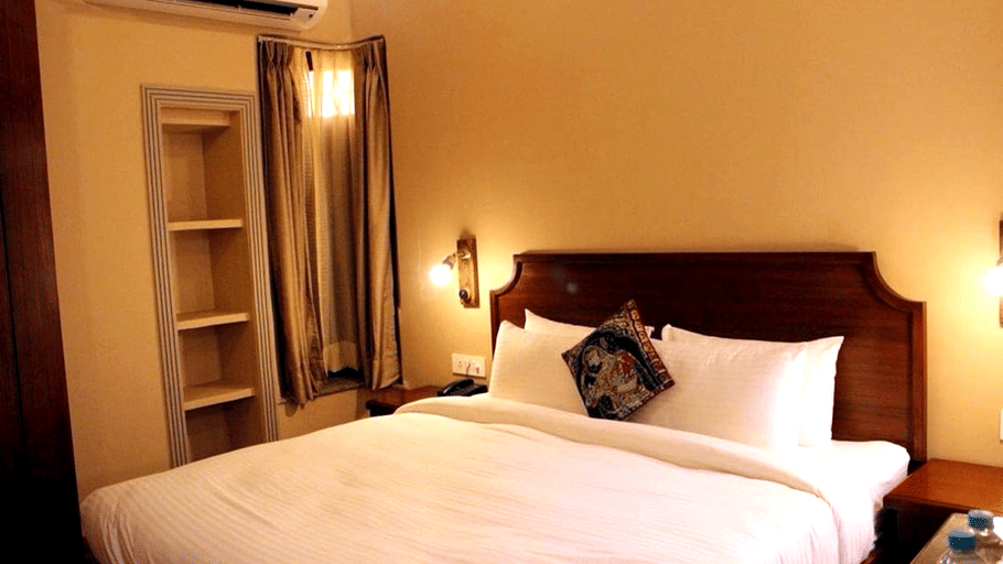 A room with a large bed, spreads, pillows, and lights. | Hotel Devnadi, Haridwar