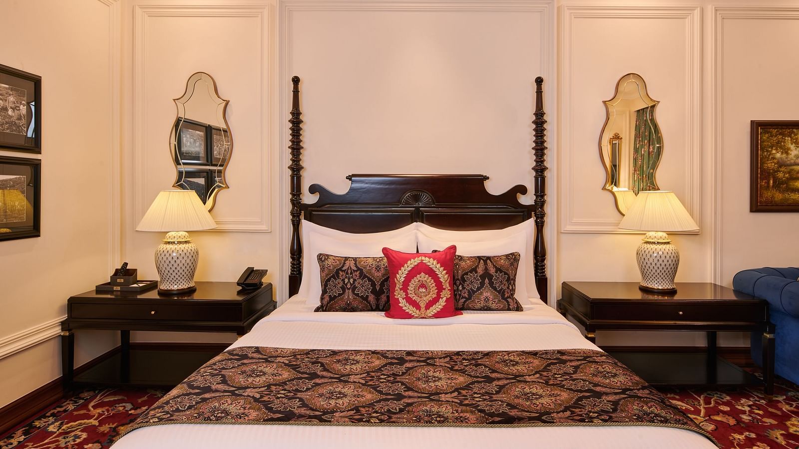 Traditional king-sized bed with ornate headboard and vintage mirrors at MAYFAIR Tea Resort, Siliguri