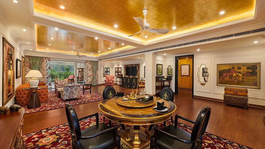 Spacious dining area with round table, chandeliers, and rich artwork.