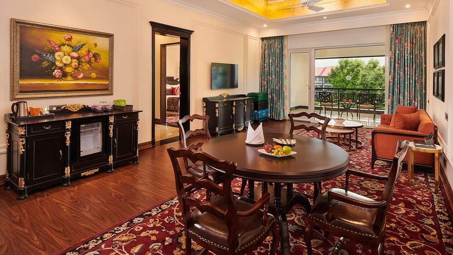 Dining area with round wooden table, classic furnishings, and large windows.
