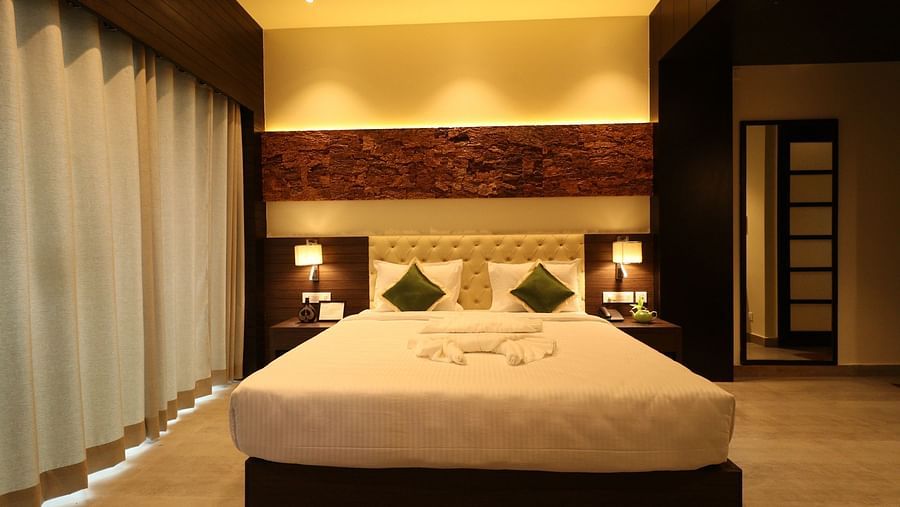 A well-lit hotel bedroom with a large bed, bedside lamps, and a wooden headboard, set in a room with warm lighting - Sea Hills Hotels, Sri Vijaya Puram (Port Blair)