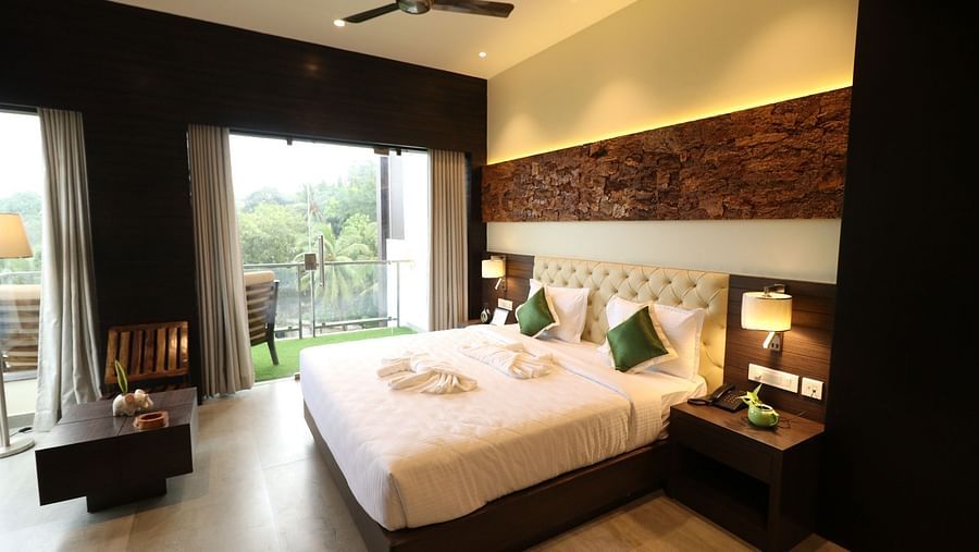 Another angle of the modern hotel bedroom, showing the large bed, bedside lamps, and the contemporary design with wooden and textured wall panels - Sea Hills Hotels, Sri Vijaya Puram (Port Blair)