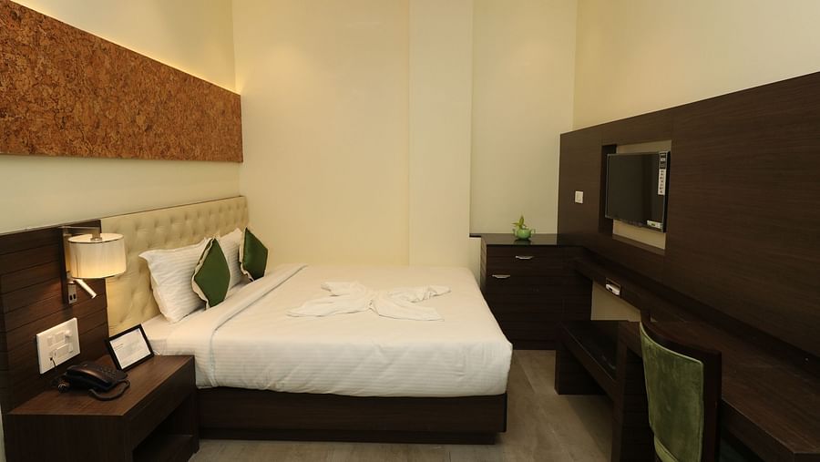 A hotel bedroom with a large bed, a wooden coffee table, and an armchair, showcasing a well-lit and comfortable space - Sea Hills Hotels, Sri Vijaya Puram (Port Blair)