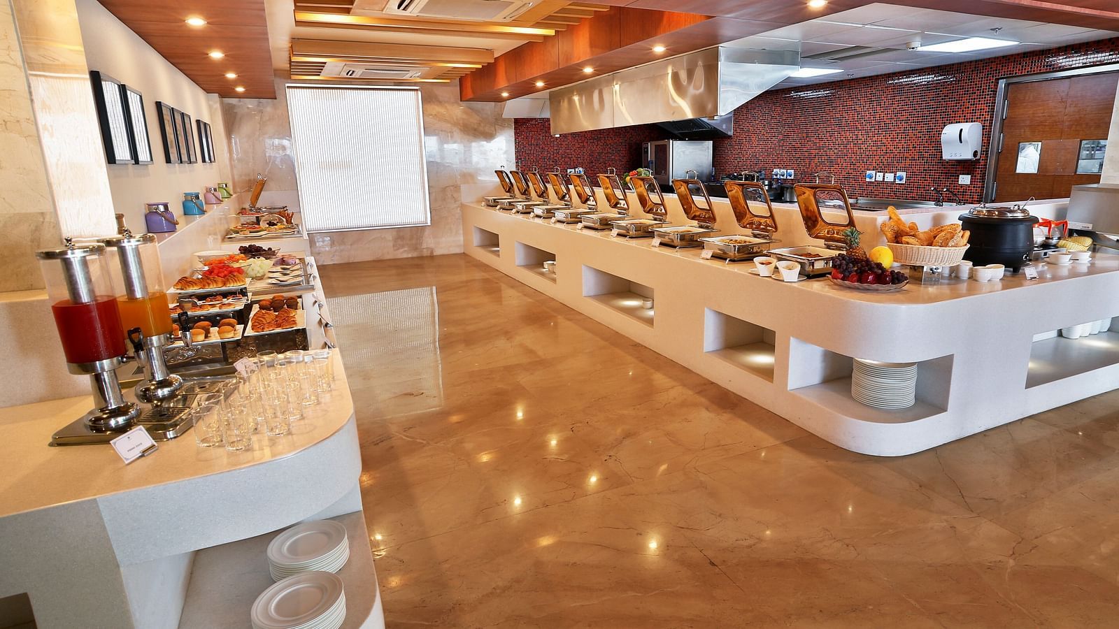A restaurant with elegant interiors and bright lighting featuring the buffet counter with a wide array of dishes served - Ramada by Wyndham, Ghaziabad, Vasundhara