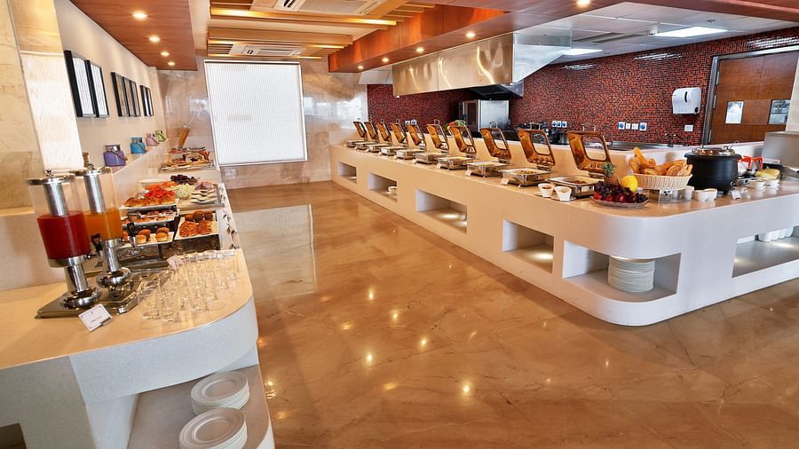 A restaurant with elegant interiors and bright lighting featuring the buffet counter with a wide array of dishes served - Ramada by Wyndham, Ghaziabad, Vasundhara