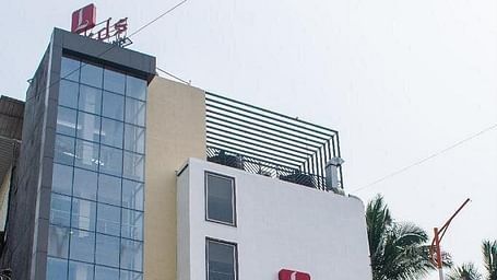 Exterior view of our hotel with multiple floors and some greenery in the background - Lords Eco Inn Belagavi