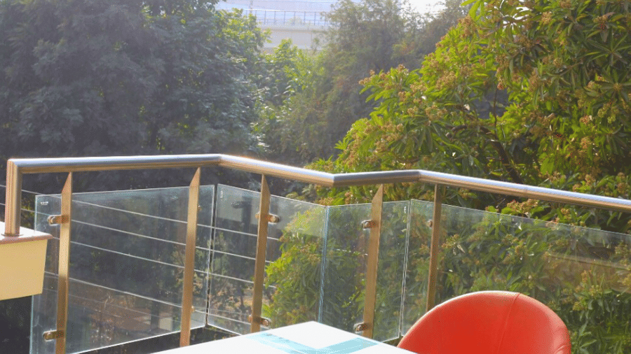 Terrace seating with a glass-top table, a red chair, and a glass-and-steel balustrade overlooking the city skyline.